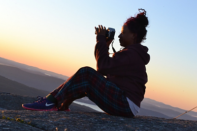 Silhouette of student with camera on mountain at sunset