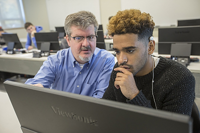 Computer science professor works with student in computer lab
