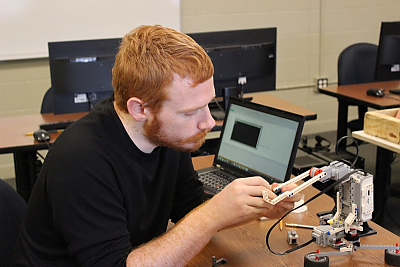 Student works on LEGO robotic arm in computer science lab