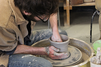 Student making pot on potter's wheel