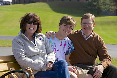 Parents and student on bench on campus