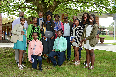 Landmark College graduate with extended family under tree on quad