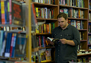 Student standing in front of bookshelves looking at book