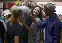 Student holds up disco ball as two other students look on; vintage hats and clothes in background